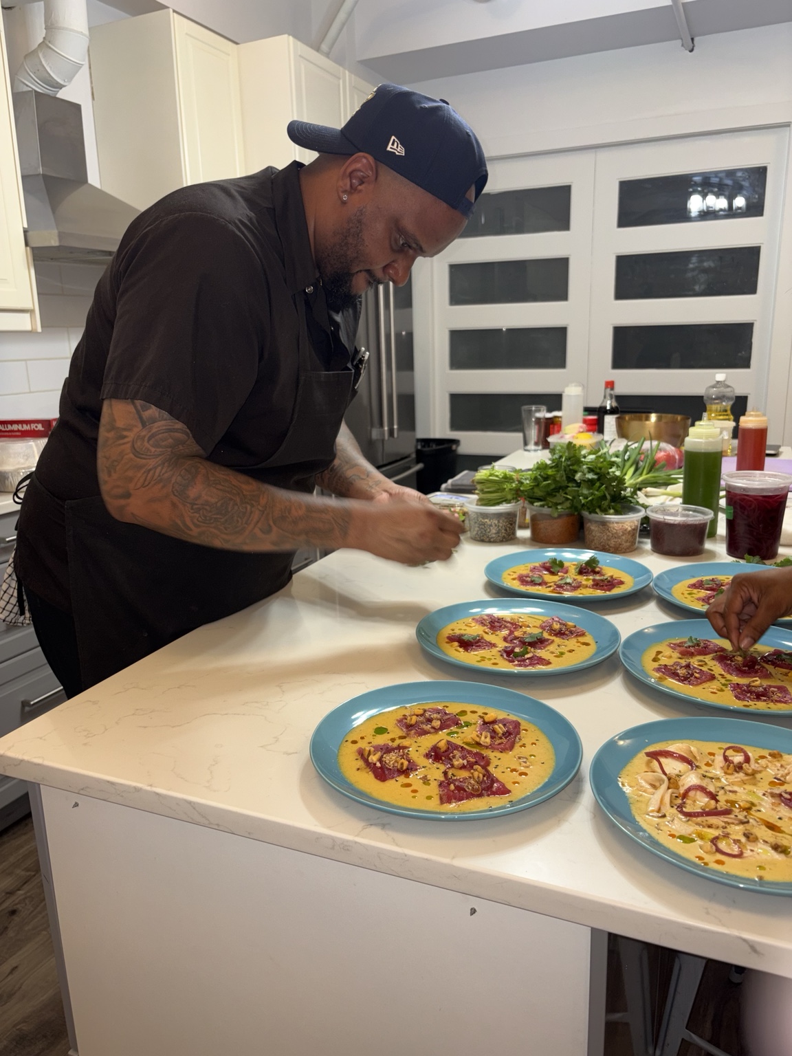 Chef Gibson preparing colourful crudo plates in a private kitchen